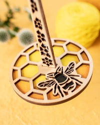 Close up image of a brightly colored wrist yarn holder featuring a honeybee.