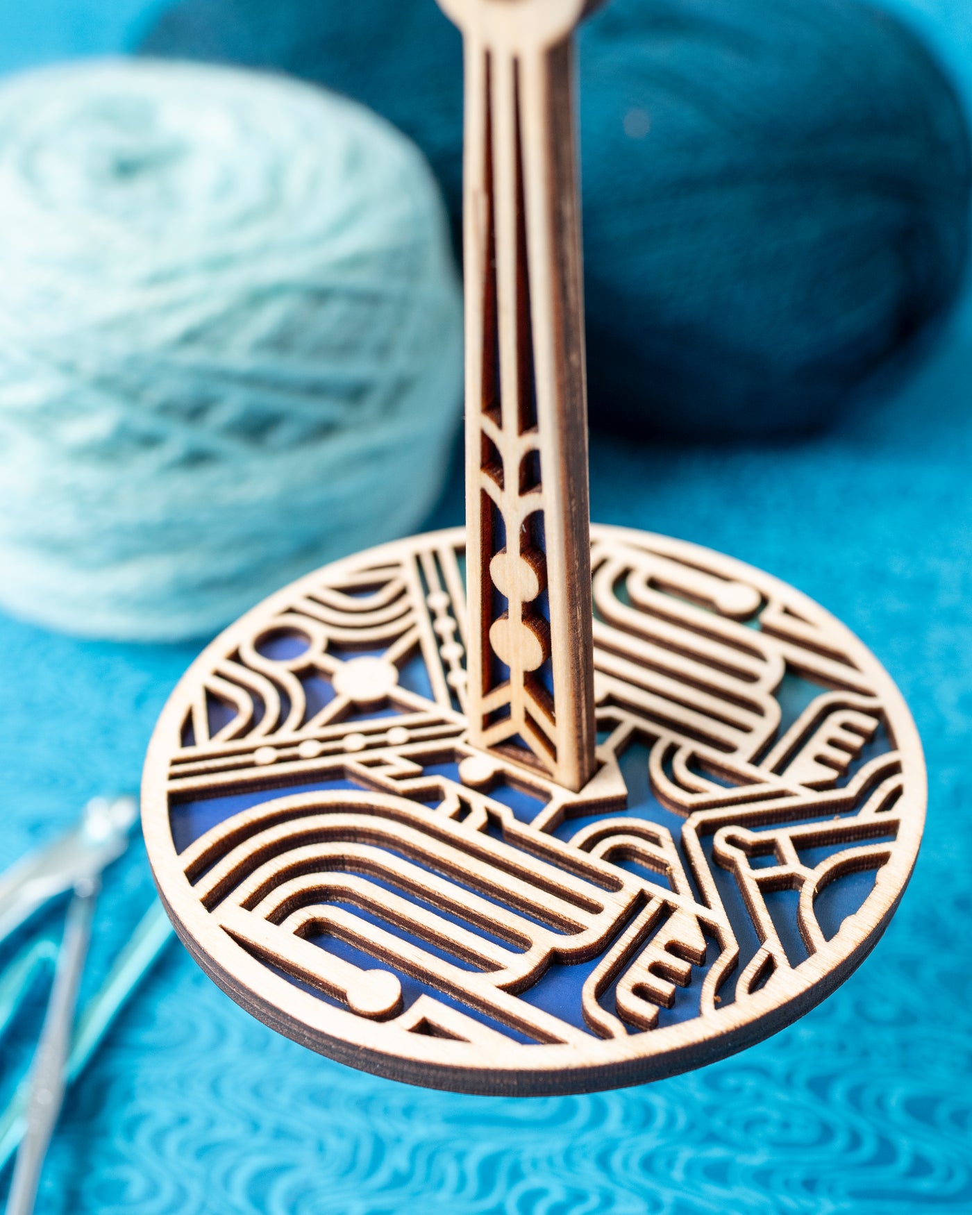 A close up image of a decorative portable yarn ball holder with a blue art deco inspired design for knitting and crochet yarn management.