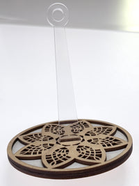 Decorative wooden yarn holder with mandala pattern with a clear center post against a white background