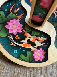 Detail shot of the one of the koi fish on the circular wooden mini minder yarn holder plate.